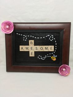 a wooden cross with flowers on it and the words be awesome spelled in scrabble