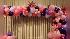 an arch made out of balloons and starbursts is displayed in front of a curtain