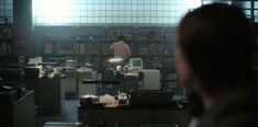 a man standing in front of a bookshelf filled with lots of book shelves