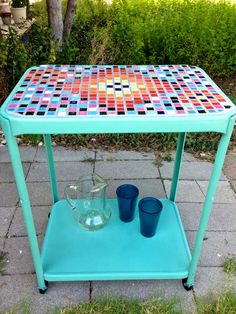 a blue table with two cups on it and a vase sitting next to the top