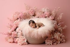 a newborn baby is curled up in a fluffy ball surrounded by pink flowers and peonies