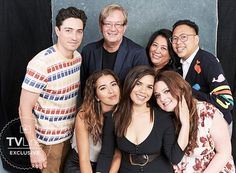 a group of people standing next to each other in front of a black backdrop and smiling