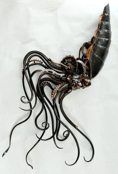 an octopus sculpture made out of metal on a white surface with black and gold accents