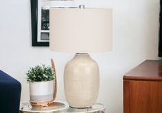 a white lamp sitting on top of a table next to a potted plant