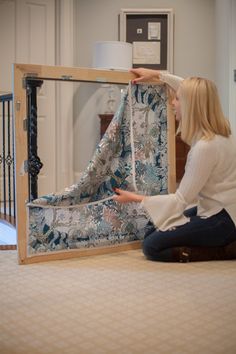 a woman sitting on the floor next to a piece of fabric in front of a mirror