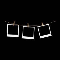 three polaroid frames hanging on a clothes line against a black background with two pegs