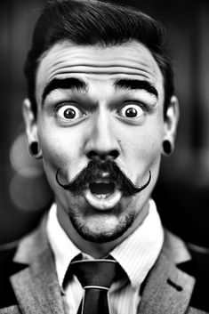 a man wearing a suit and tie with fake mustaches on his face looking surprised