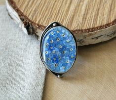 ✿ Adjustable antique Silver Plated Ring with real dried Forget me not flowers. ✿ SIZE: - Bezel size is 30x22 mm (1 3/16 x 7/8 inch)  - Depth of the bezel is 5 mm (7/32 inches) - Weight of the ring is 15 grams. ✿ Ring is oxidized silver plated Brass. Ring is adjustable. ✿ Only genuine dried mushrooms and plants where used in the process of making this piece, as well as all other items in this shop. ✿ Every piece in this shop was made in several casting steps, sanded and polished by hand. ✿ This item was made using special Eco resin, which is crystal clear, UV stable, doesn't have any smell to it and is absolutely safe for your health. ✿ ✿ Resin is a very strong material and, in contrast to glass, it can not break! ✿ ✿ All items are shipped in a GIFT BOX, you don't have to pay extra for the Forget Me Not Ring, Forget Me Not Flowers, Dried Mushrooms, Jewelry Real, Flowers Dried, Eco Resin, Floral Ring, Flower Jewelry, Brass Ring