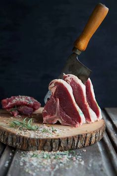 a piece of raw meat on a wooden cutting board with a knife stuck in it