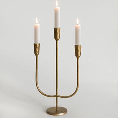 three candles are lit on a brass candelabra