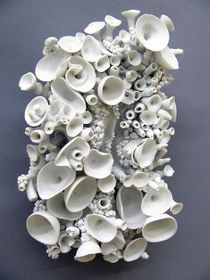 an arrangement of white vases are arranged on a gray surface and placed in the shape of flowers