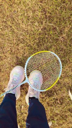 a person standing in the grass holding a tennis racquet with their feet up