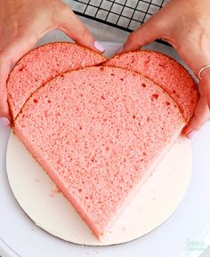 a heart shaped cake on a plate being held by two hands