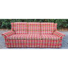 a red and yellow plaid couch sitting on top of a gravel road next to bushes