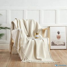 a white blanket sitting on top of a wooden chair next to a potted plant