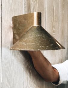 a man is holding up a light fixture on the wall in front of a wood paneled wall