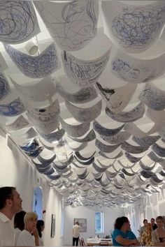 many people are standing in a room with paper decorations on the ceiling