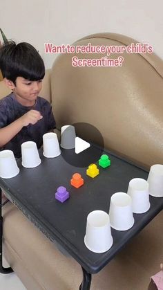 a little boy sitting at a table with cups on it