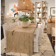 a dining room table with chairs and a plant in a vase on the centerpiece