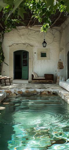 an outdoor swimming pool surrounded by stone walls and greenery next to a patio area