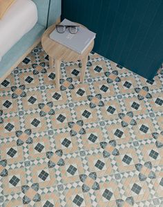 a small table sitting on top of a tiled floor next to a blue wall and bed