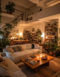 a living room filled with lots of furniture and bookshelves next to a stair case