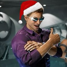 a man wearing sunglasses and a santa hat giving the thumbs up