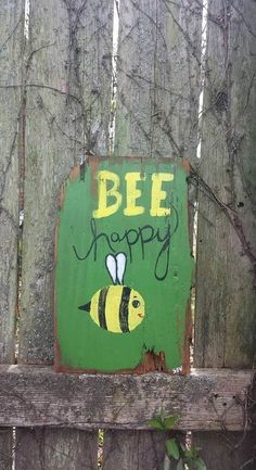 a wooden fence with a sign that says bee happy on it and a painting of a bum