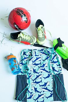 various sports items laid out on a white surface including a soccer ball, water bottle and gym bag