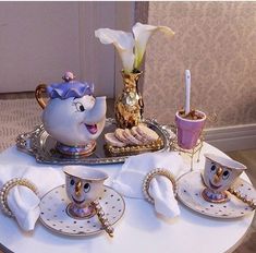 the table is set with teapots and cups on it, which are decorated with flowers