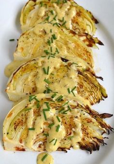 grilled artichokes on a white plate topped with gravy and garnish