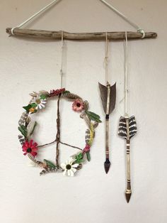 a wall hanging made out of branches with flowers and arrows attached to the branch, next to an arrow