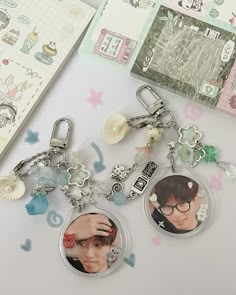 two key chains with pictures on them sitting next to a notepad and other items