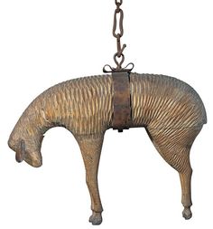 a metal horse hanging from a chain on a white background in the shape of a cow