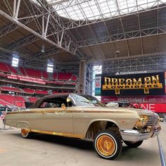 an old car is parked in front of a stadium