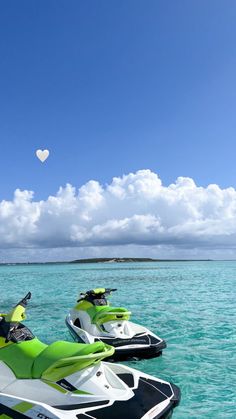 two jet skis are parked in the water near one another on a sunny day