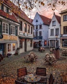 an old town with tables and chairs on the cobblestone street in front of buildings