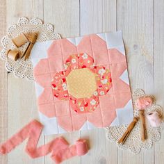 a piece of pink and white quilt next to some sewing supplies on a wooden table