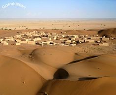 an aerial view of a desert village in the middle of the desert, with sand dunes surrounding it