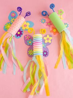 colorful paper flowers and butterfly decorations on a pink background with streamers in the shape of butterflies