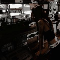 a woman standing in front of a record player at a music store with her back turned to the camera