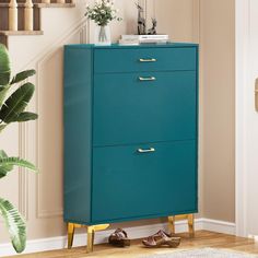 a blue cabinet with gold handles in a living room next to a stair case and potted plant