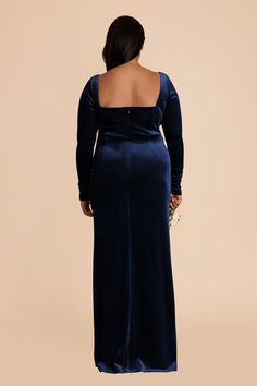 the back of a woman in a long blue dress, with her hands on her hips