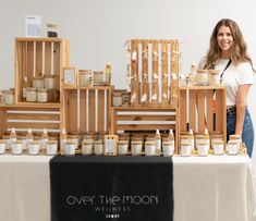 a woman standing next to a table full of jars