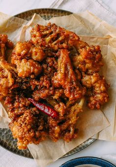 a plate full of fried food on top of a white table cloth with blue plates and utensils