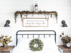 a bed with white sheets and pillows in front of a sign that says be our guest