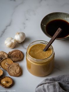 a jar filled with peanut butter next to some nuts and an onion on a table