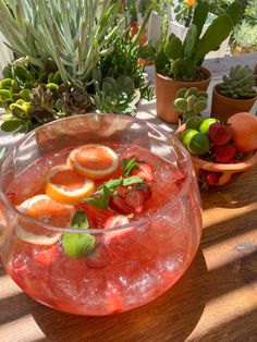 a bowl filled with fruit sitting on top of a table next to potted plants