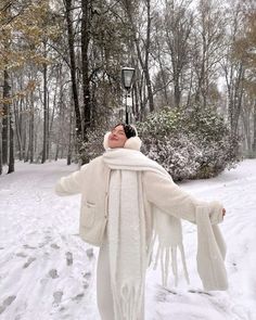 a woman standing in the snow with her arms outstretched