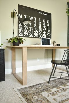 a desk with a laptop on it in front of a chalkboard